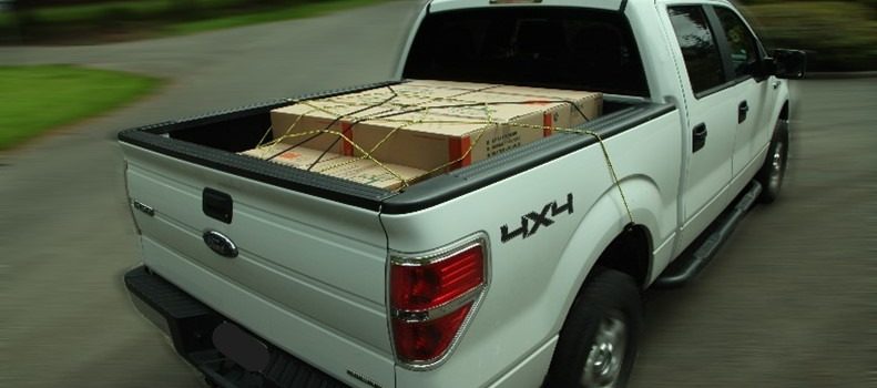 White truck with a secured load in the truck bed.