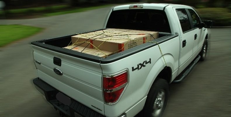 White truck with a secured load in the truck bed.