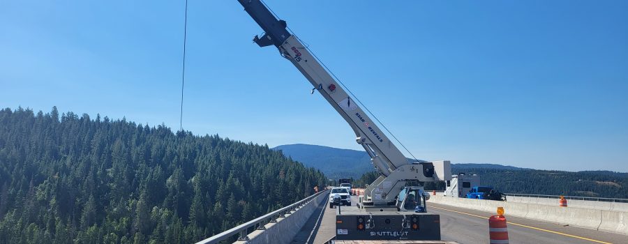 A crane lowers equipment over the side of the Veterans Memorial Bridge on I-90.