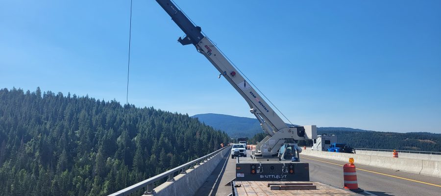 A crane lowers equipment over the side of the Veterans Memorial Bridge on I-90.