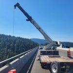 A crane lowers equipment over the side of the Veterans Memorial Bridge on I-90.