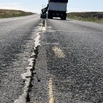 Road of SH-33 in Idaho, showing a notch ground into the pavement where paint will be applied and a truck in the background.