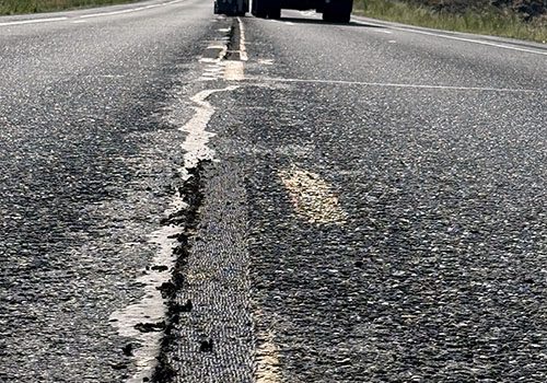 Road of SH-33 in Idaho, showing a notch ground into the pavement where paint will be applied and a truck in the background.