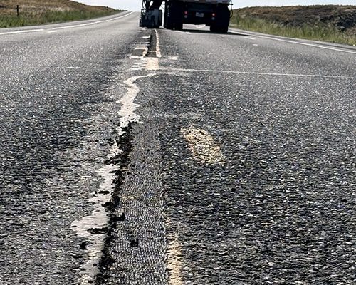 Road of SH-33 in Idaho, showing a notch ground into the pavement where paint will be applied and a truck in the background.