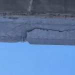Picture of significant concrete damage on a highway overpass.