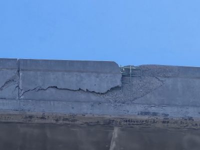 Loose, crumbling cement separating from overhead bridge