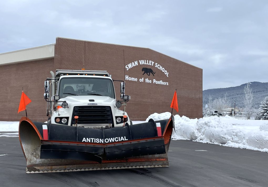 Snowplow positioned outside a school with "Antisnowcial" on the blade.