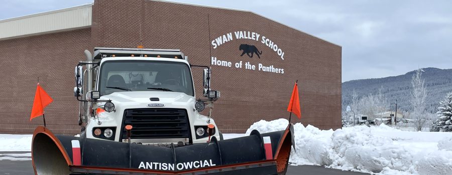 Snowplow positioned outside a school with the name "Antisnowcial" on the blade.