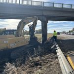 Damaged bridge with a backhoe working in the foreground.