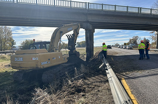 Damaged bridge with a backhoe working in the foreground.