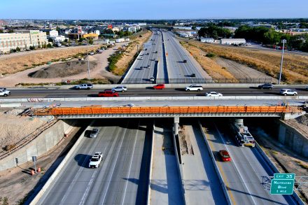 Under construction bridge nearly finished spanning expressway.