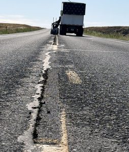A notch in the pavement at the center line of SH-33 behind an Idaho Transportation Department striping truck.