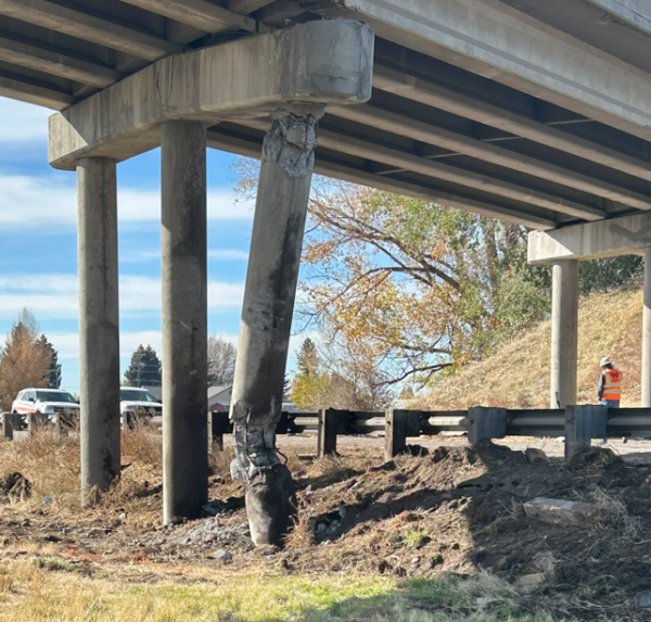 A badly damaged column hangs from the pier cap beneath a bridge. Rebar and shattered concrete are visible.