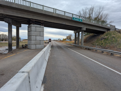 A concrete barrier protects a temporary pier supporting Riverton Road leaving the main driving lane open for traffic.