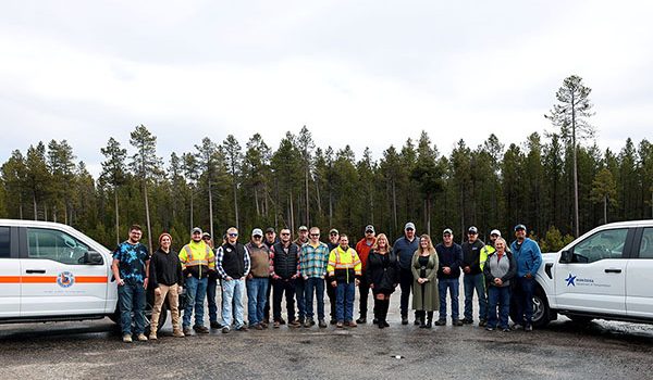 A large group of Operations employees from ITD and MDT between vehicle with both state logos on them.