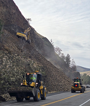 Loaders can be seen working in tandem near the base of the slope on US-12 near Arrow bridge.