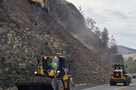 Loaders can be seen working in tandem near the base of the slope on US-12 near Arrow bridge.