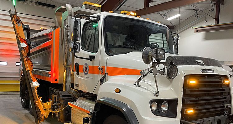 ITD snowplow inside shop building with orange and green lights flashing.