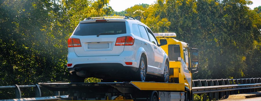 Yellow tow truck with white SUV being towed away.