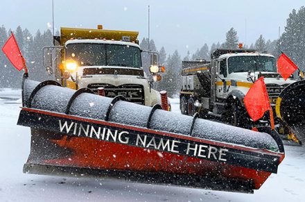 Picture of two ITD snowplows parked side by side on a snowy day near Potlatch, Idaho. The front of the blade says "WINNING NAME HERE" in all capital letters.