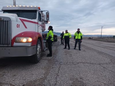 ITD employees speaking with a truck driver positioned behind the wheel of his truck at a Port of Entry.