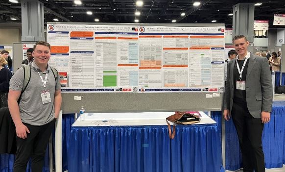 Two men stand in front of award winning research study at DC Conference.