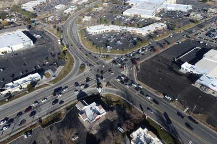 Aerial drone photo looking south along Blue Lakes Boulevard at its signalized intersection with Pole Line Road in Twin Falls, Idaho, surrounded by commercial development and parking lots.