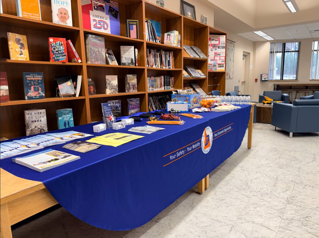 A table draped with an ITD tablecloth and set with pamphlets, fliers, handouts, and snacks for the US-95 Corridor Safety Workshop