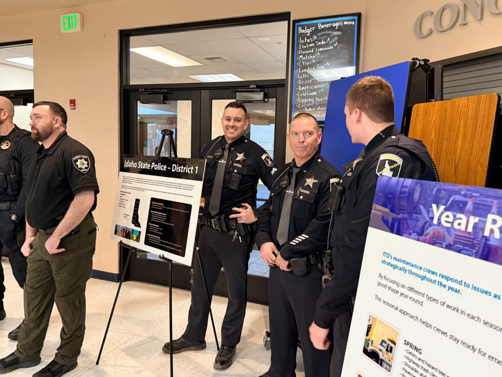 Troopers from Idaho State Police pose for a photo next to display boards at the US-95 Corridor Safety Workshop.