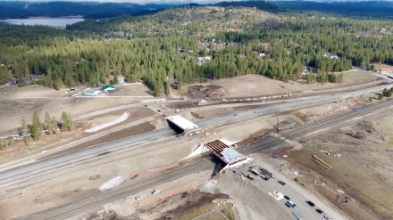 Aerial view of the interchange bridges in construction over the existing highway and over the adjacent railroad tracks.