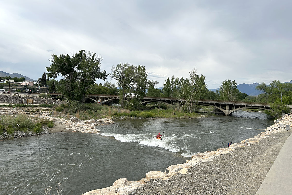 US-93 bridge over the Salmon River facing north with kayakers in the whitewater park of the river.