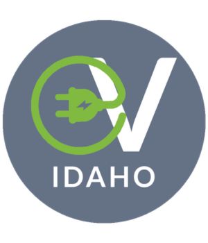 Idaho NEVI Program logo featuring a green electric plug forming a circular outline around the letters ‘EV’ with ‘Idaho’ below on a gray background.