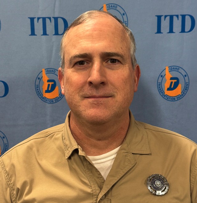 Michael Fisher stands looking at the camera in front of an ITD backdrop.