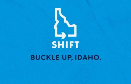 Blue graphic with an outline of Idaho, a right‑pointing arrow inside it, and the words ‘SHIFT’ and ‘Buckle Up, Idaho.