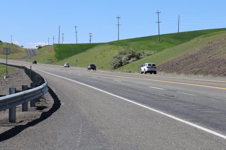 Vehicles travel along a divided section of U.S. Highway 95 through green hills in north-central Idaho.