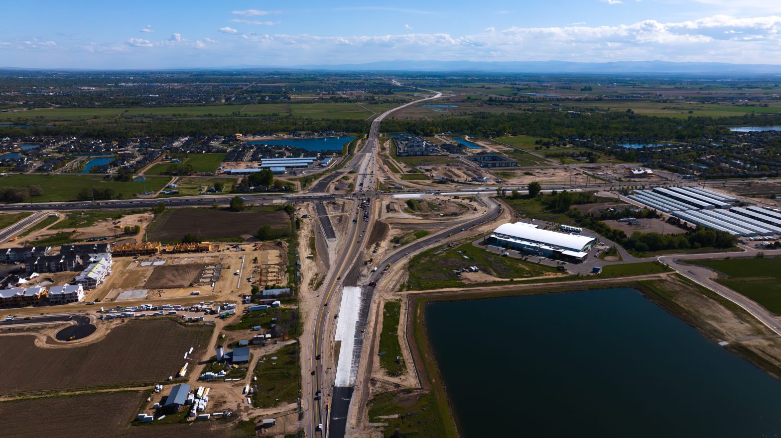 Overhead drone photo of a complex construction area of two highway surrounded by farmland.
