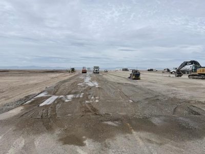 Construction equipment and crews work on a section of State Highway 167 where damaged pavement is being removed and rebuilt following an aircraft crash.