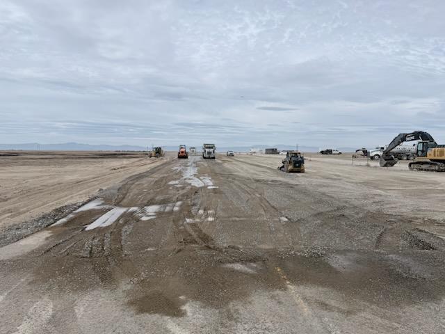 Construction equipment and crews work on a section of State Highway 167 where damaged pavement is being removed and rebuilt following an aircraft crash.
