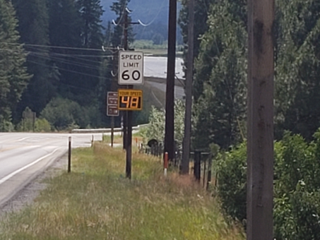 Digital speed sign beneath a speed limit sign on a pole next to a highway. 