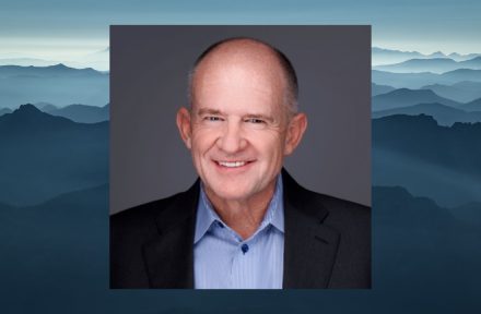 ITD District 6 Board Member Cortney Liddiard smiles at the camera. His headshot is imposed over a scenic view of Idaho mountains.