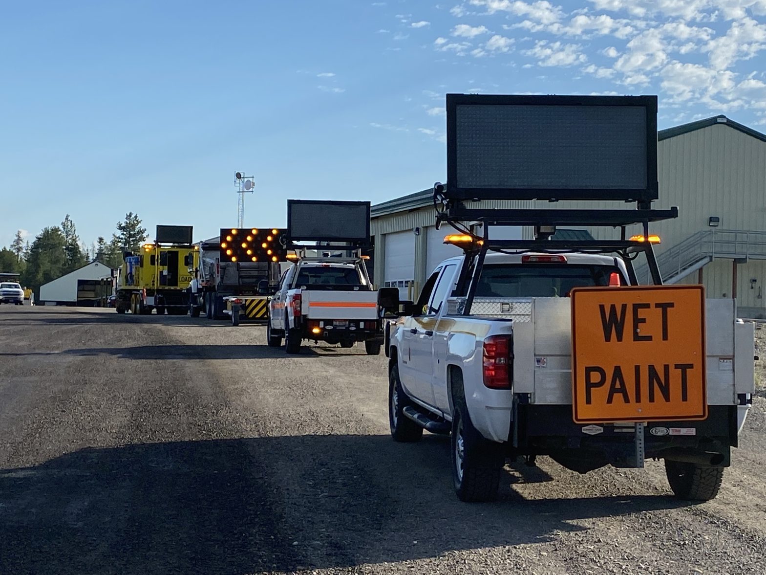 A mobile striping operation consisting of the paint truck and support vehicles with signs directing traffic.