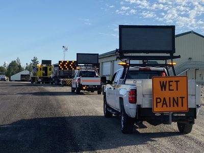 A mobile striping operation consisting of the paint truck and support vehicles with signs directing traffic.