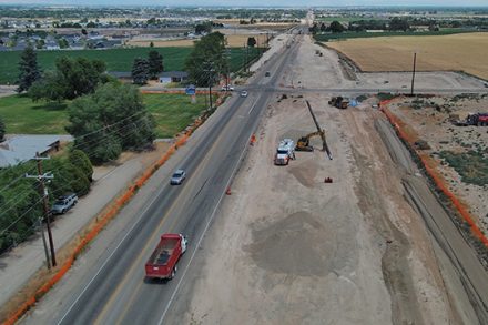 Aerial view of construction on SH-55 near Montana Avenue, with traffic shifted to one side while crews work on a widened roadway section.