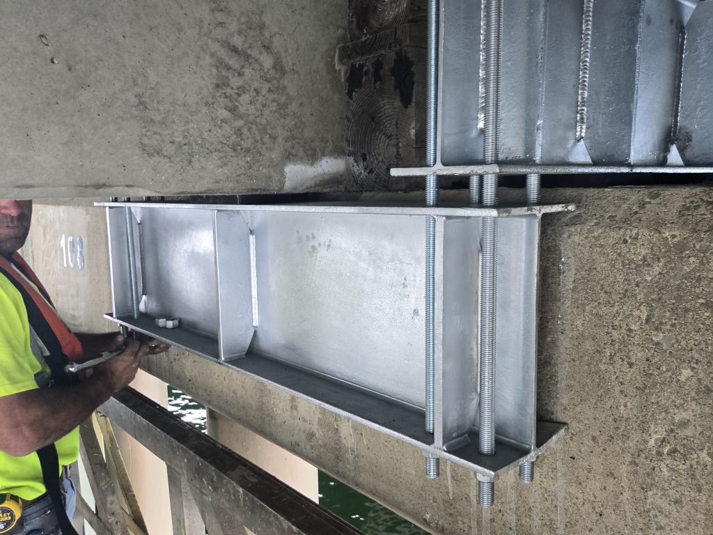 Custom steel brackets installed beneath a bridge.