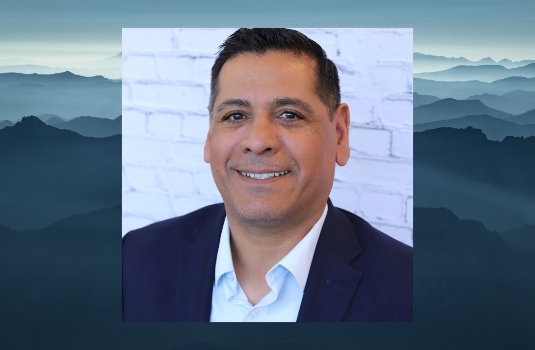 ITD Director Alberto Gonzalez headshot over a scenic image of Idaho mountains.