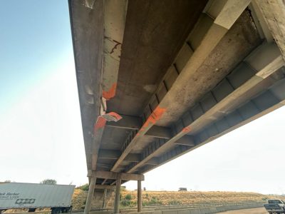 Bridge damage with metal girder hanging from bottom of bridge.