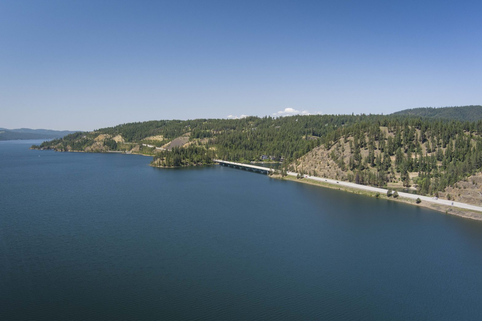 Aerial side view of Blue Creek Bay bridge stretching over part of Lake Coeur d'Alene.