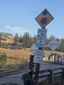 Bridge weight limit signs showing an 8-ton gross vehicle weight limit and 3.9-ton axle weight limit stand at the entrance to the East Kooskia Bridge.