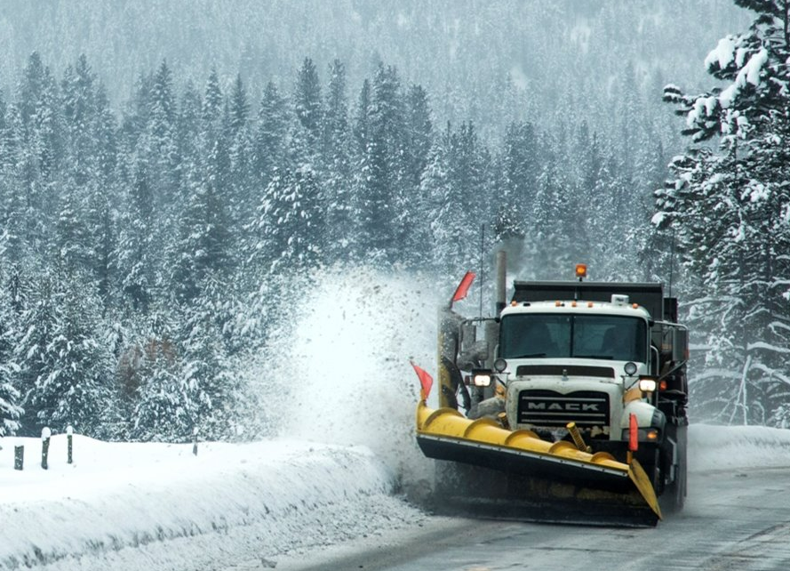 A snowplow working on a snowy, rural road.