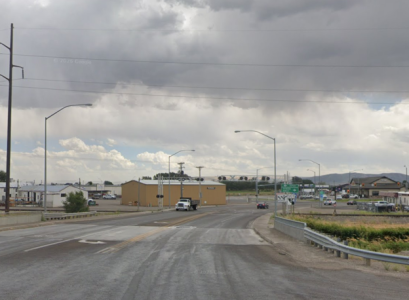 Four-lane highway crossing railroad tracks near an adjacent intersection on a cloudy day.